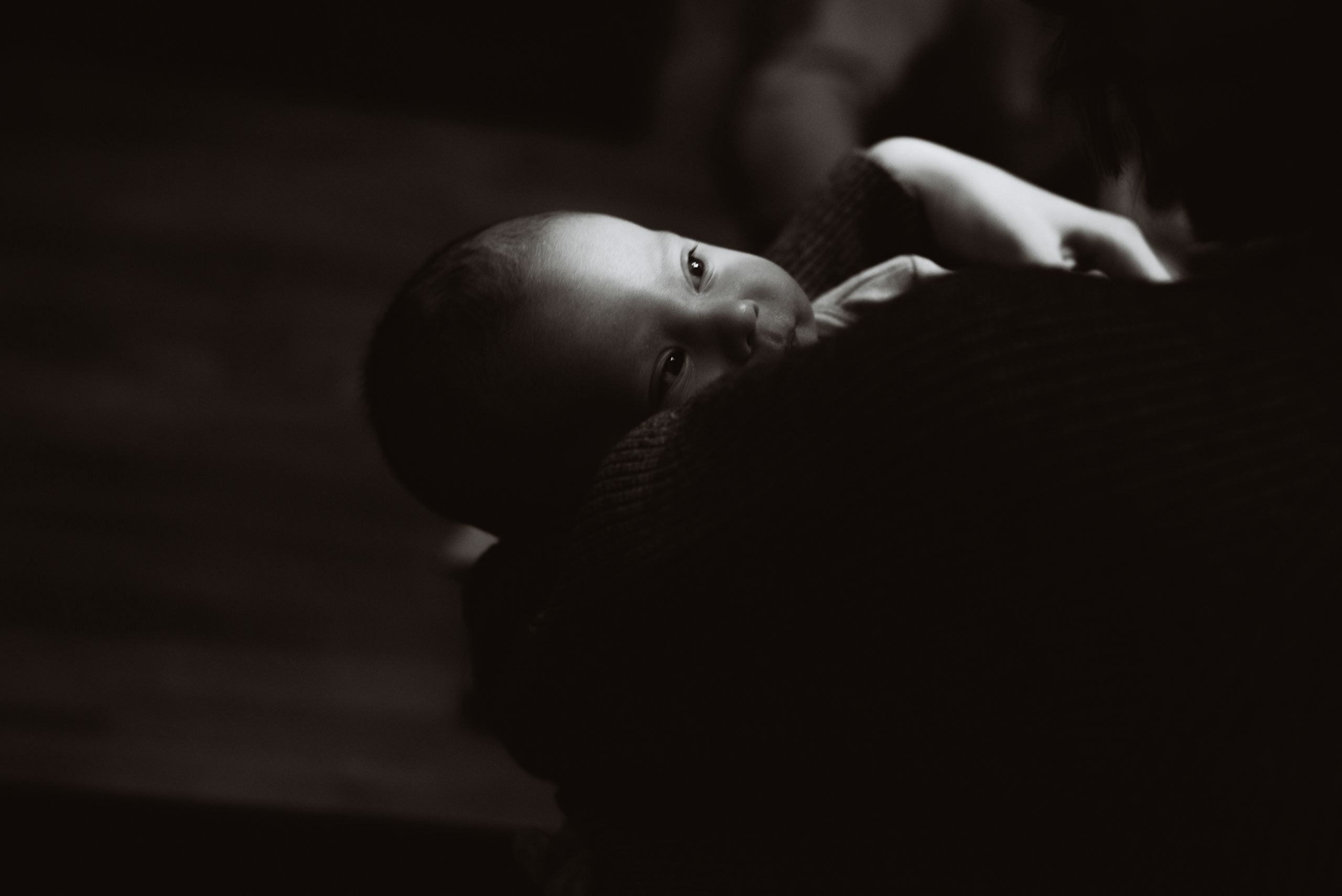 Emotive black and white capture of a baby cradled in a loving embrace, highlighting innocence.