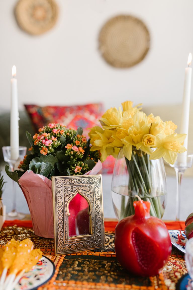 Vibrant Nowruz celebration table with candles, flowers, and traditional decor.